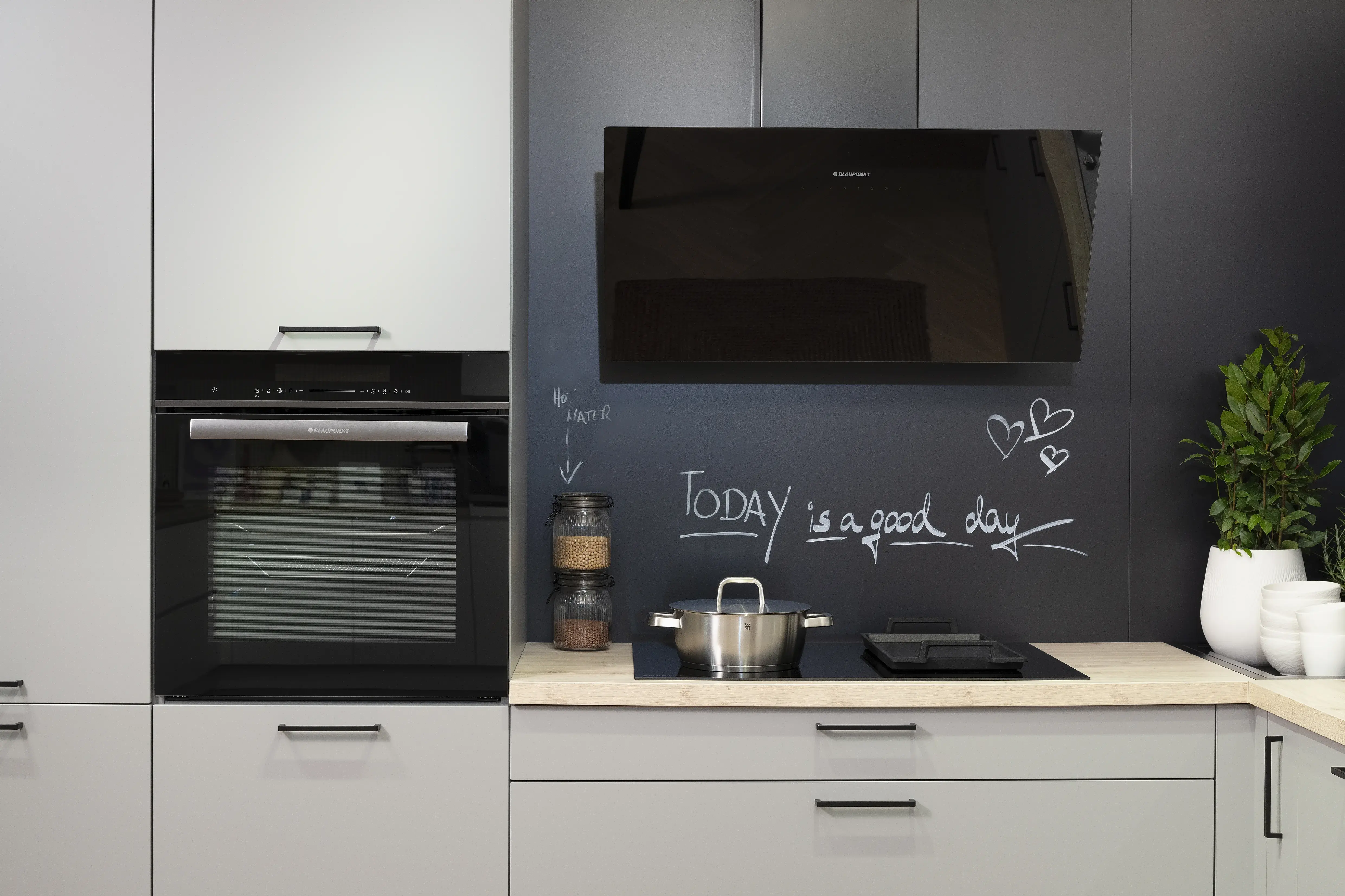 Häcker-Küche in Perlgrau mit Kochfeld, Backofen und Kopffreihaube von Blaupunkt. 