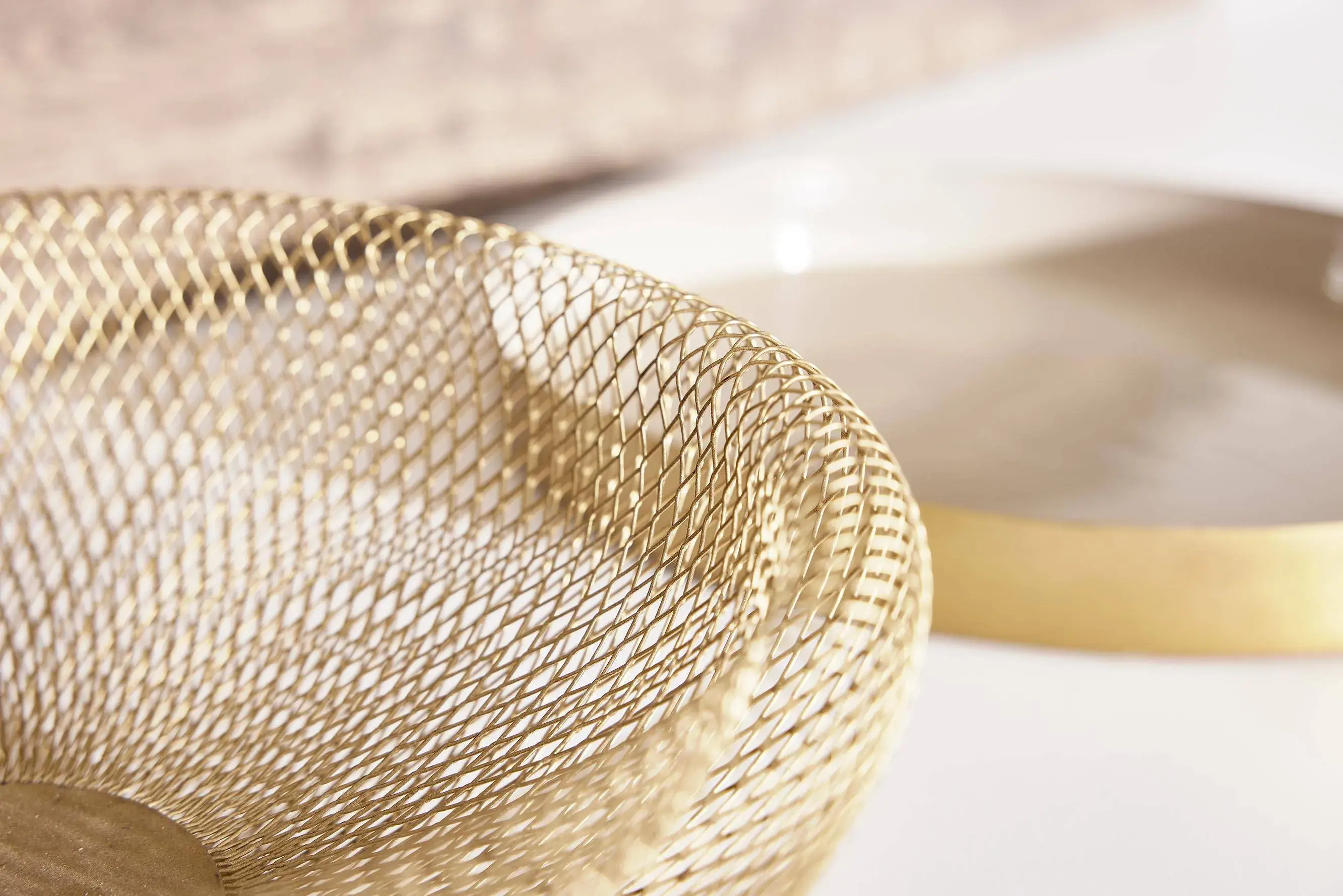 NOBILIA Alpinweiß Moodshot - Metalschale aus goldenem Draht als Fokus-/Detailaufnahme mit weichgezeichnetem Hintergrund